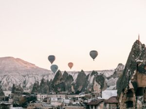 Globos de aire sobrevolando la ciudad situada entre formaciones rocosas al atardecer